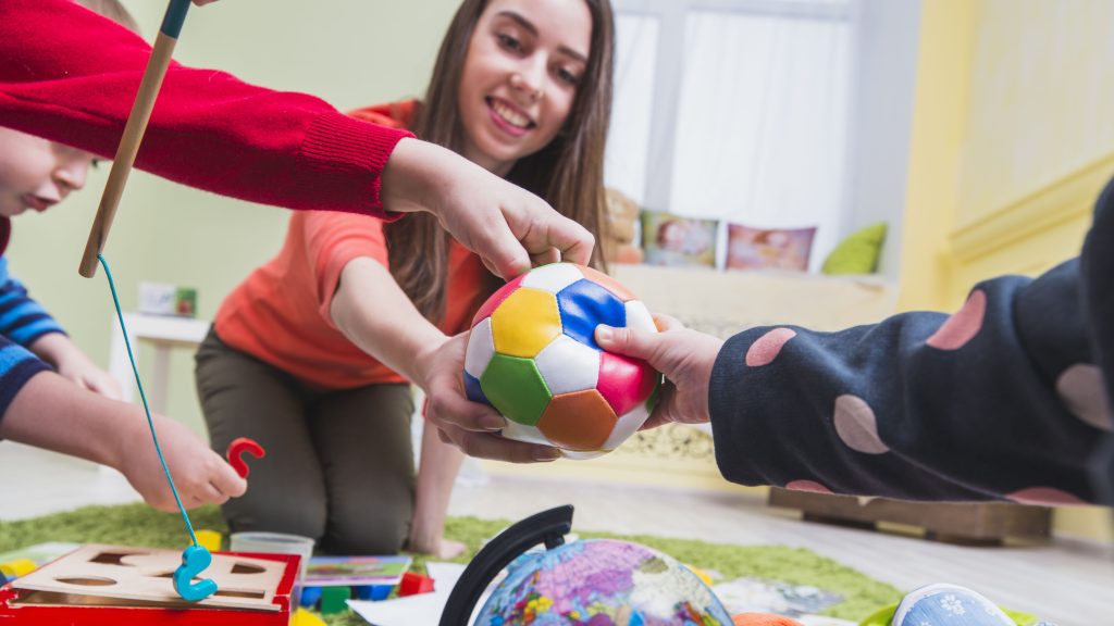 Crianças realizando atividades lúdicas com terapeuta ocupacional, utilizando brinquedos para estimular habilidades motoras e cognitivas.